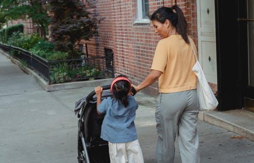 Ethnic mother helping daughter in carrying stroller